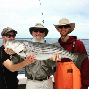 Grandfather and Grandsons holding striped bass